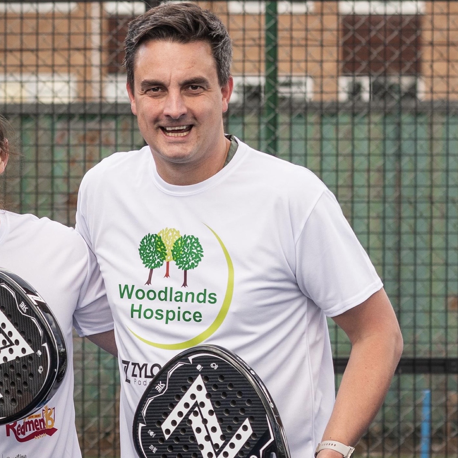 Daniel Nicolson with padel rackets and a Woodlands Hospice shirt